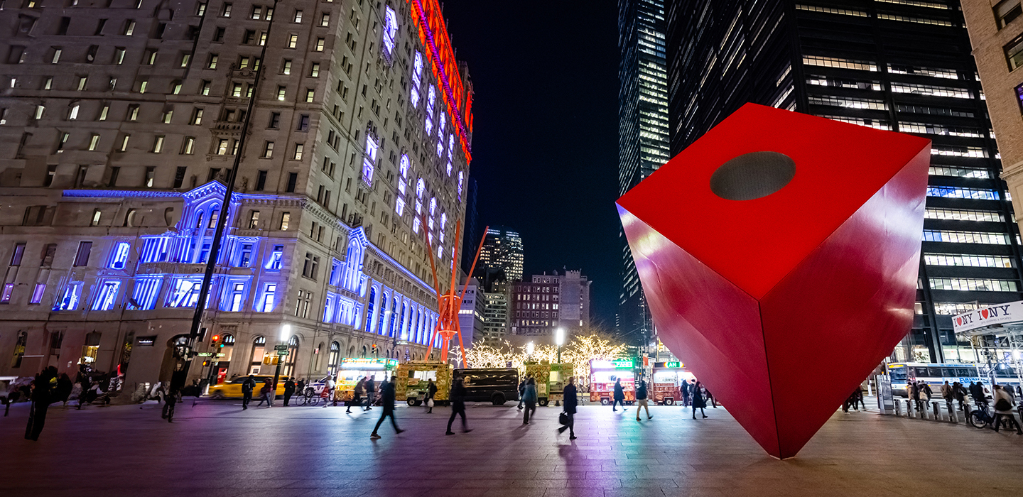Photo of the red cube sculpture in New York City at night.